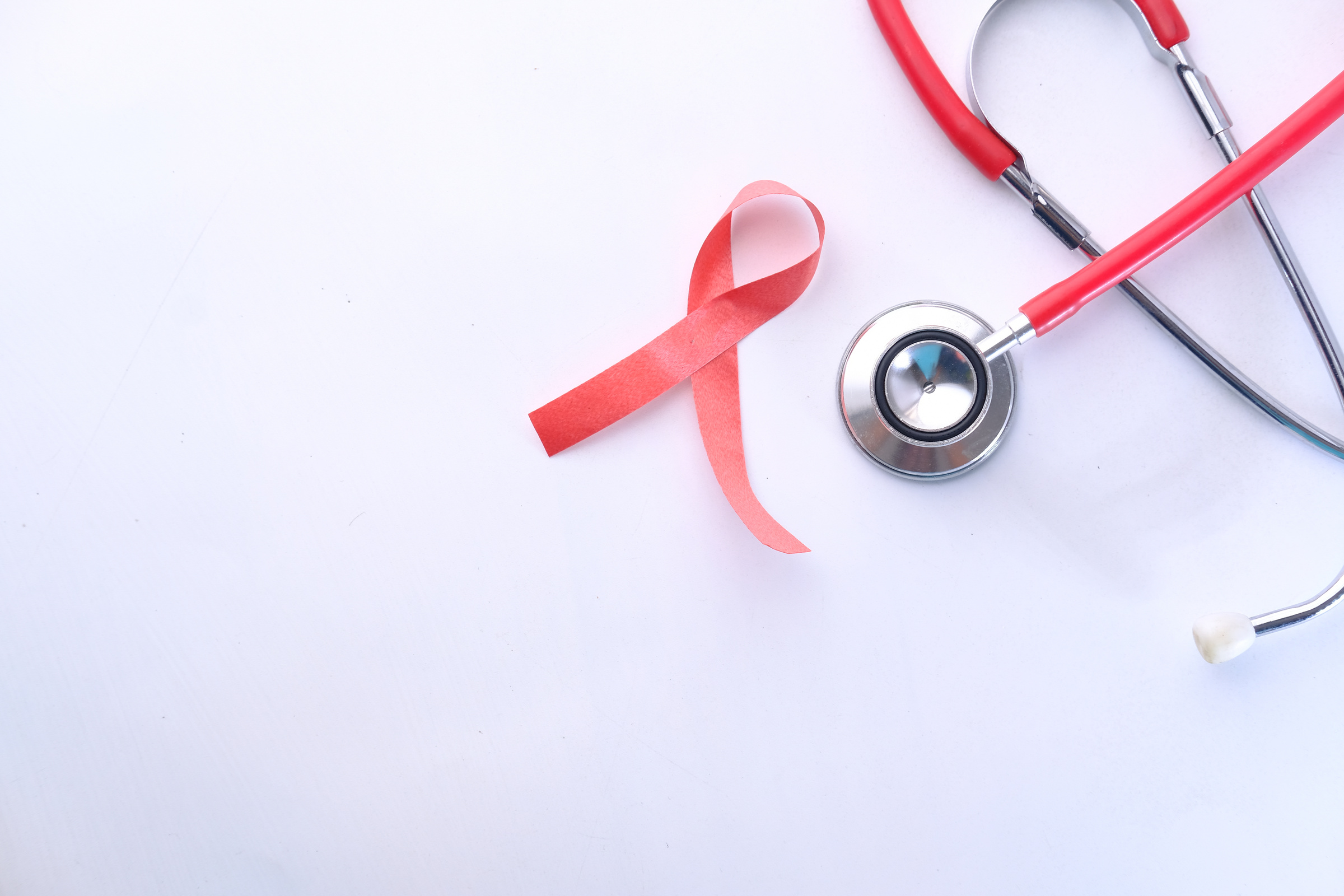 Red Ribbon HIV, and Stethoscope on White Background.